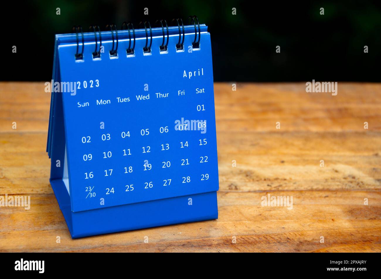 April 2023 blue desk calendar on wooden table background with ...