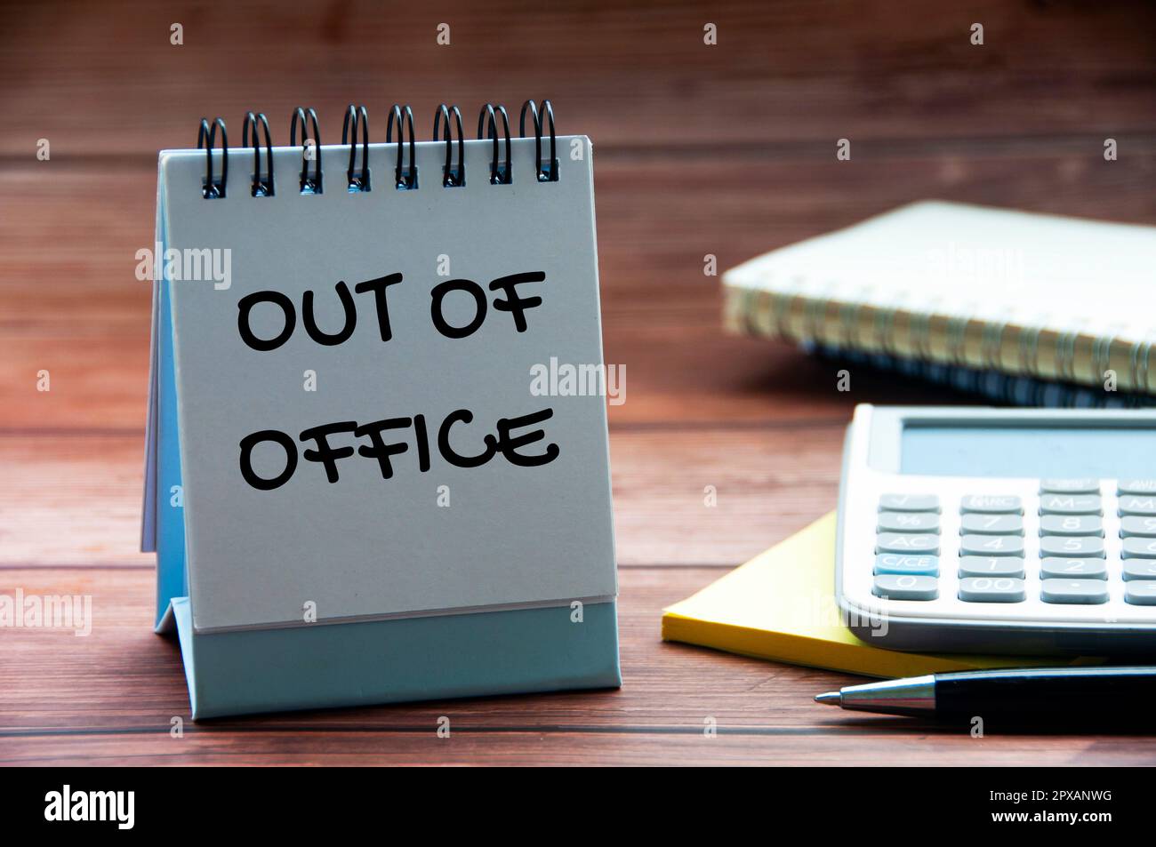 Out of office text on calendar desk with notebook, calculator and pen background. Out of office concept Stock Photo