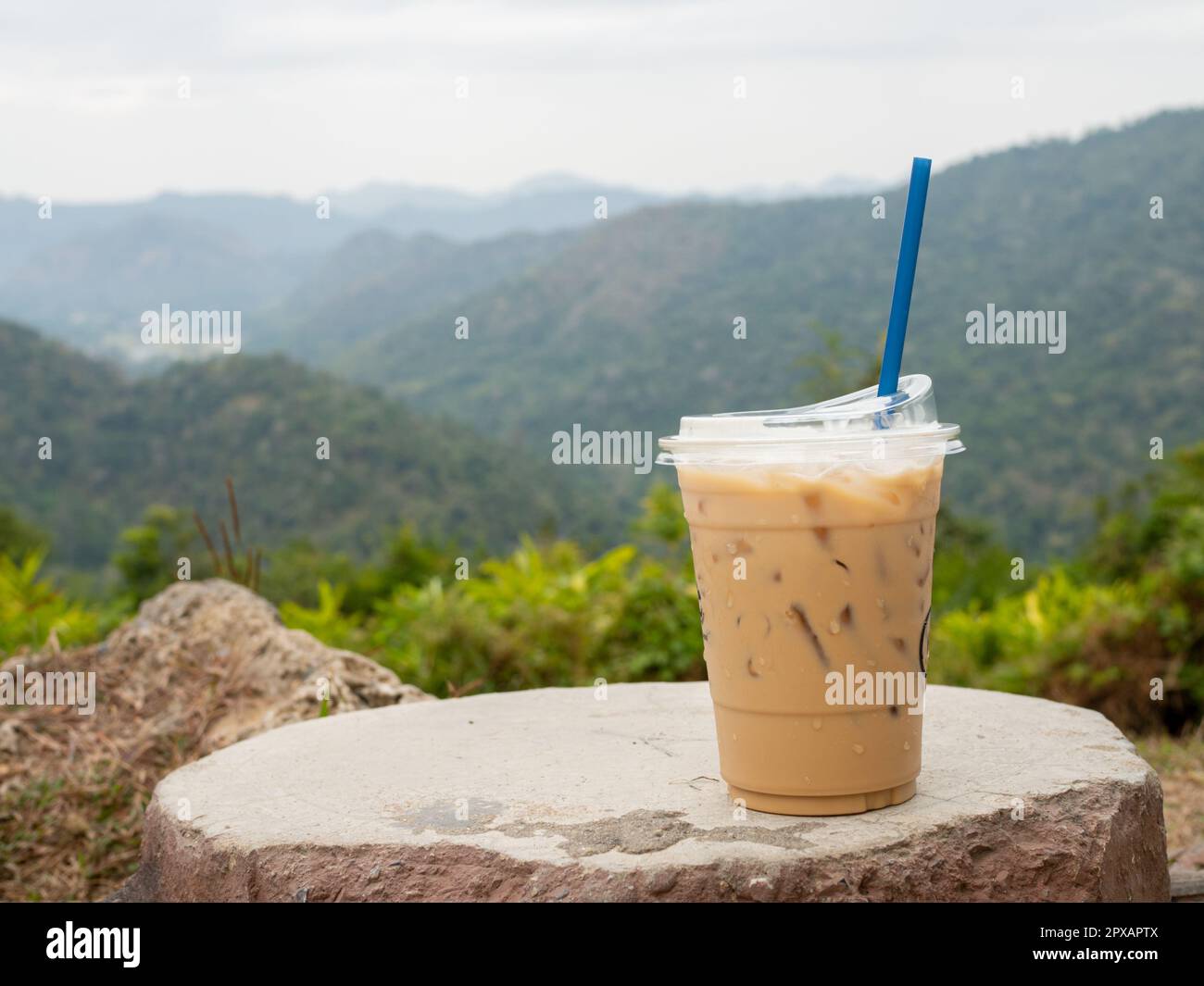 https://c8.alamy.com/comp/2PXAPTX/a-glass-of-iced-coffee-is-placed-on-a-rock-against-a-background-of-mountains-and-sky-2PXAPTX.jpg
