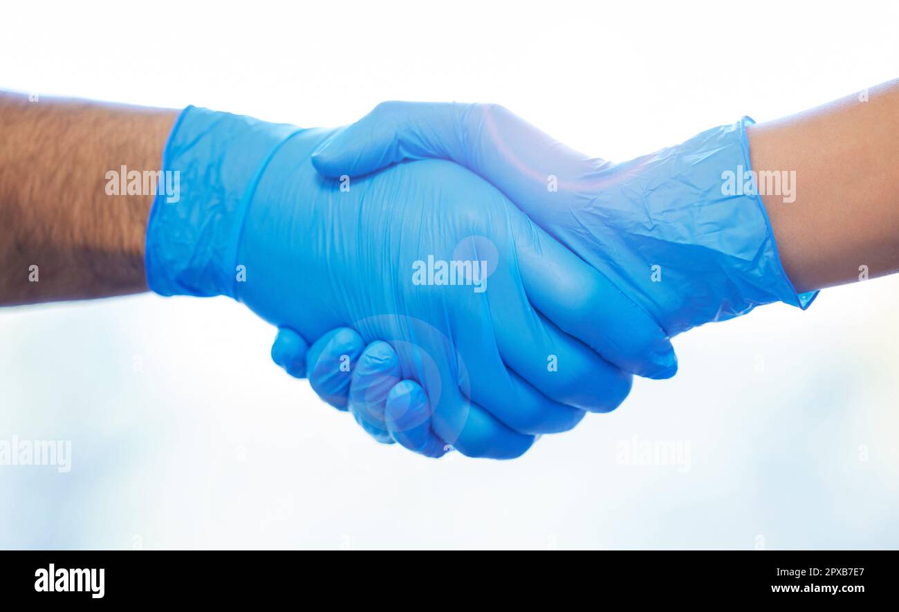 A deal is a deal. two unrecognisable dentists wearing gloves and shaking hands. Stock Photo