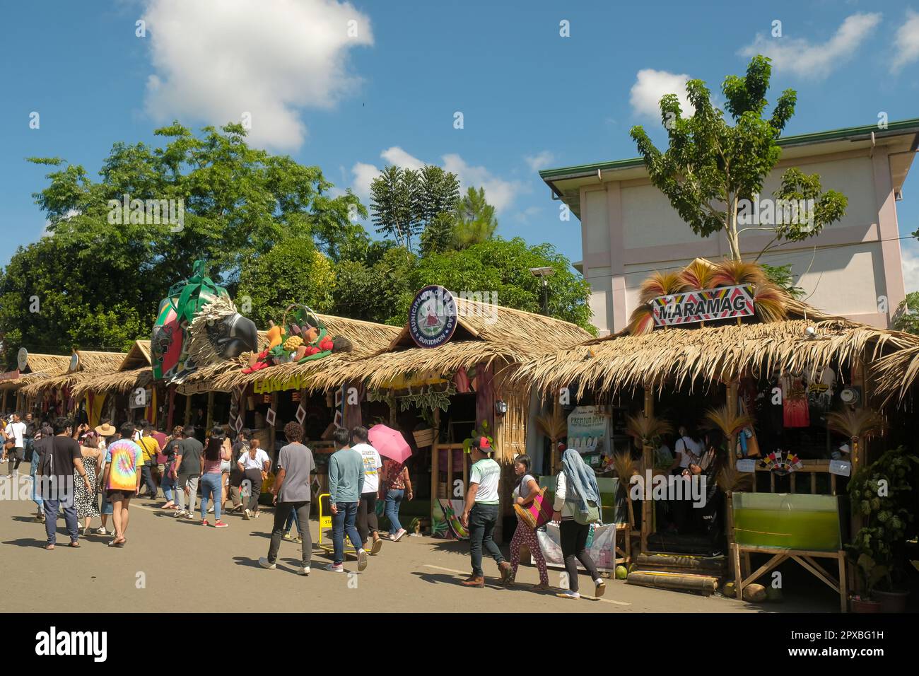 Malaybalay City, Philippines - people walk on busy street with decorated nipa huts as pop-up local stores at the annual Kaamulan Festival in Bukidnon. Stock Photo