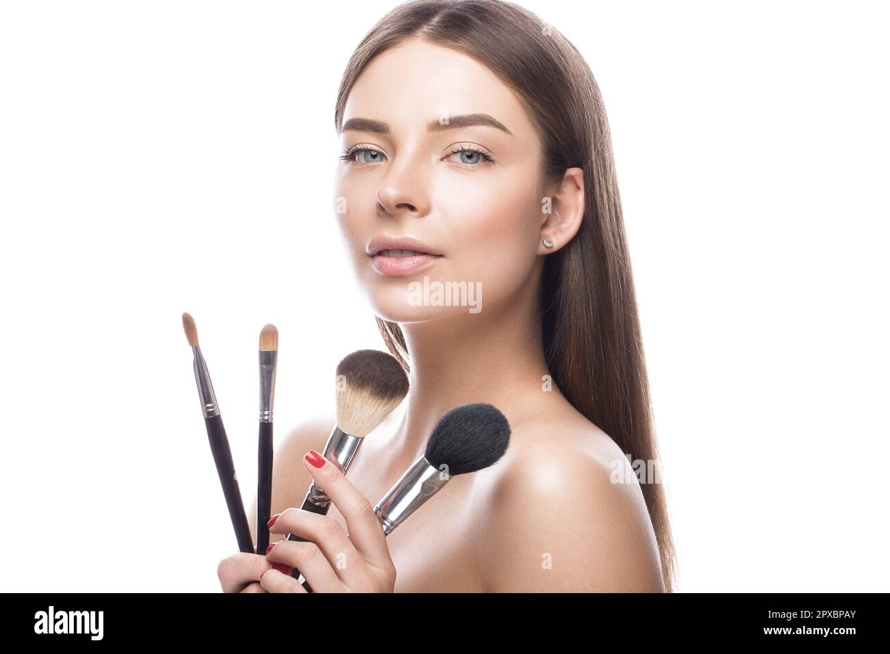 Beautiful young girl with a light natural makeup,brushes for cosmetics and perfect skin. Beauty
