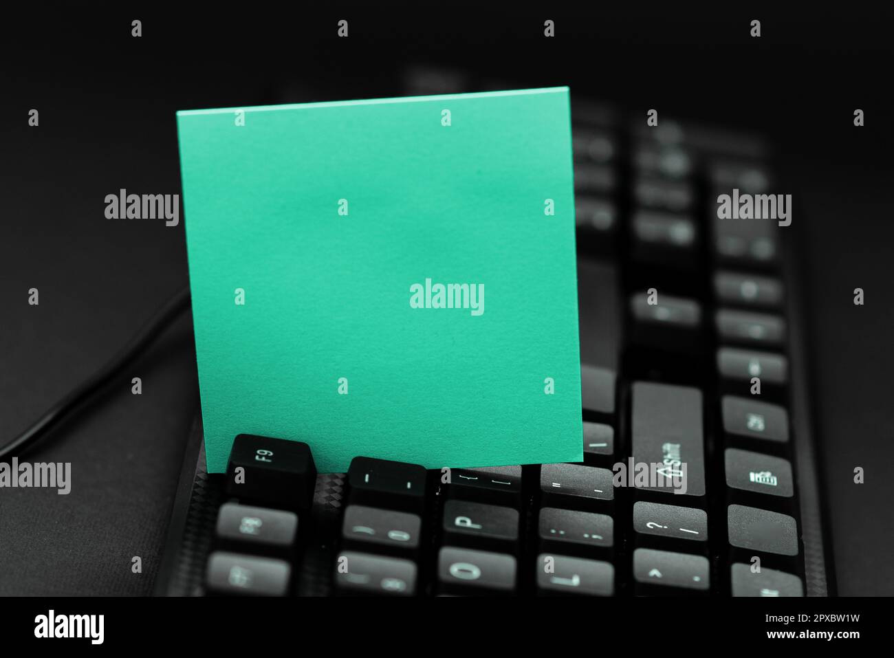 Colored sticker lying on keyboard. Important message written over paper. Stock Photo