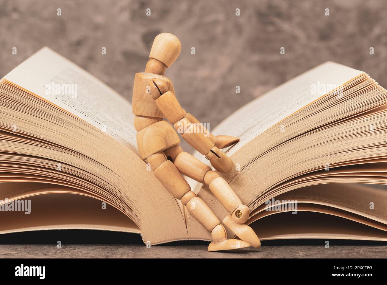 Wooden mannequin sitting on the open book. Reading Books Shows Learning