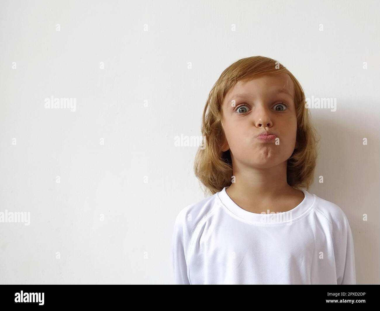 Little cute girl with blond hair on a white background. Tanned skin