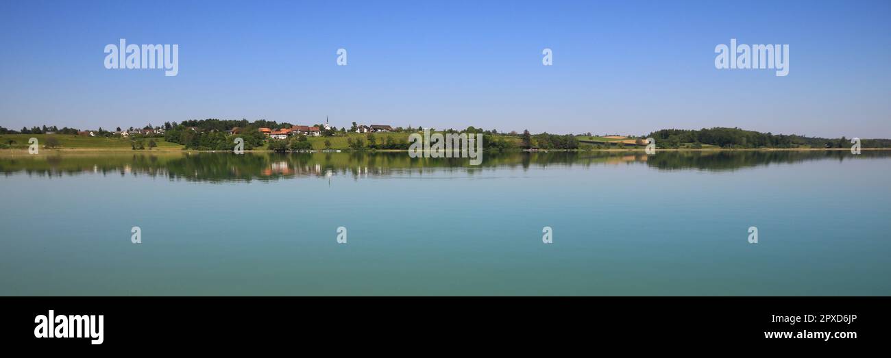 Village Seegraben and green meadows reflecting in Lake Pfaffikon. Stock Photo