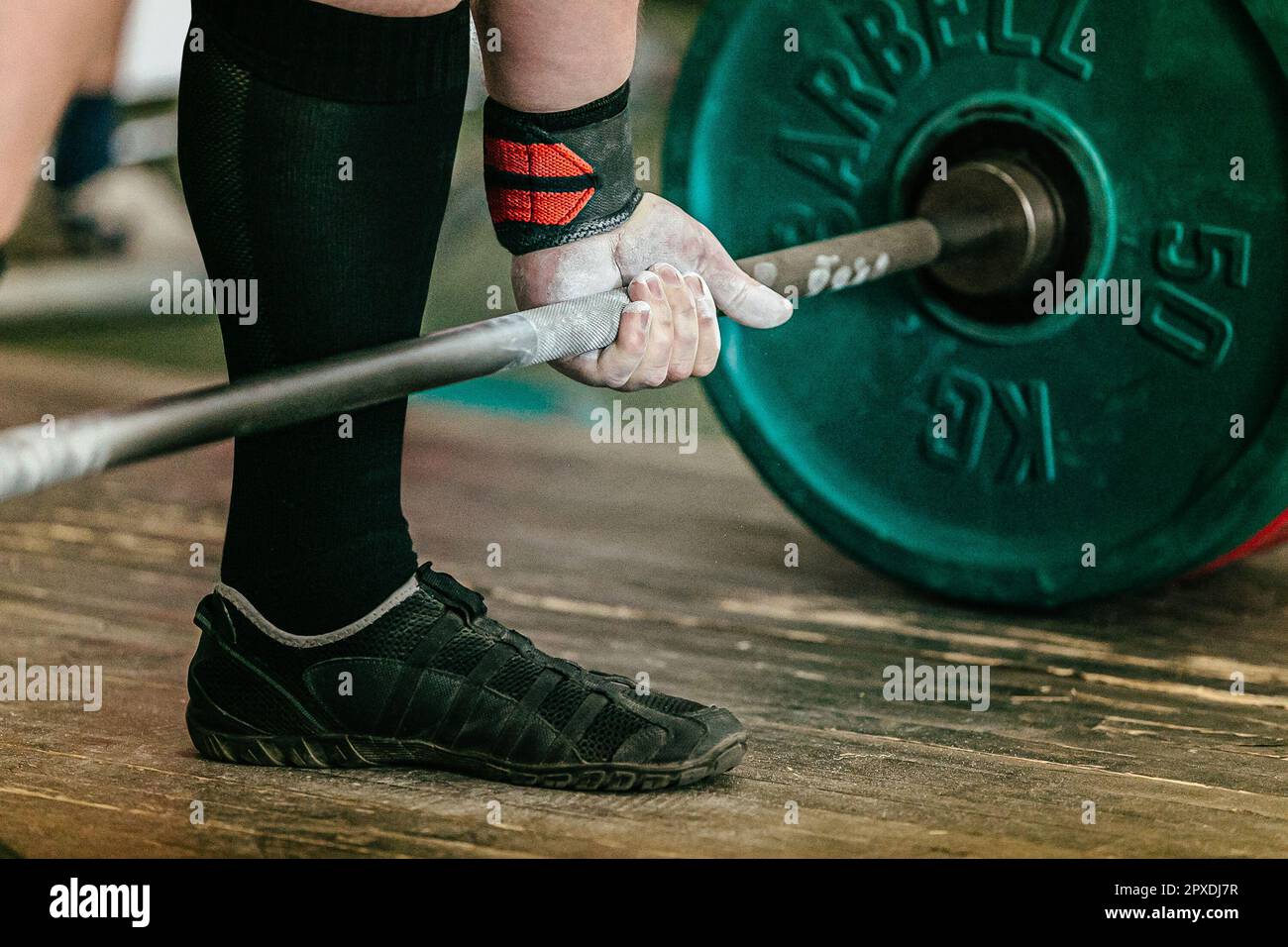 athlete powerlifter performing deadlift heavy barbell, hand in wrist wraps with applied gym chalk Stock Photo