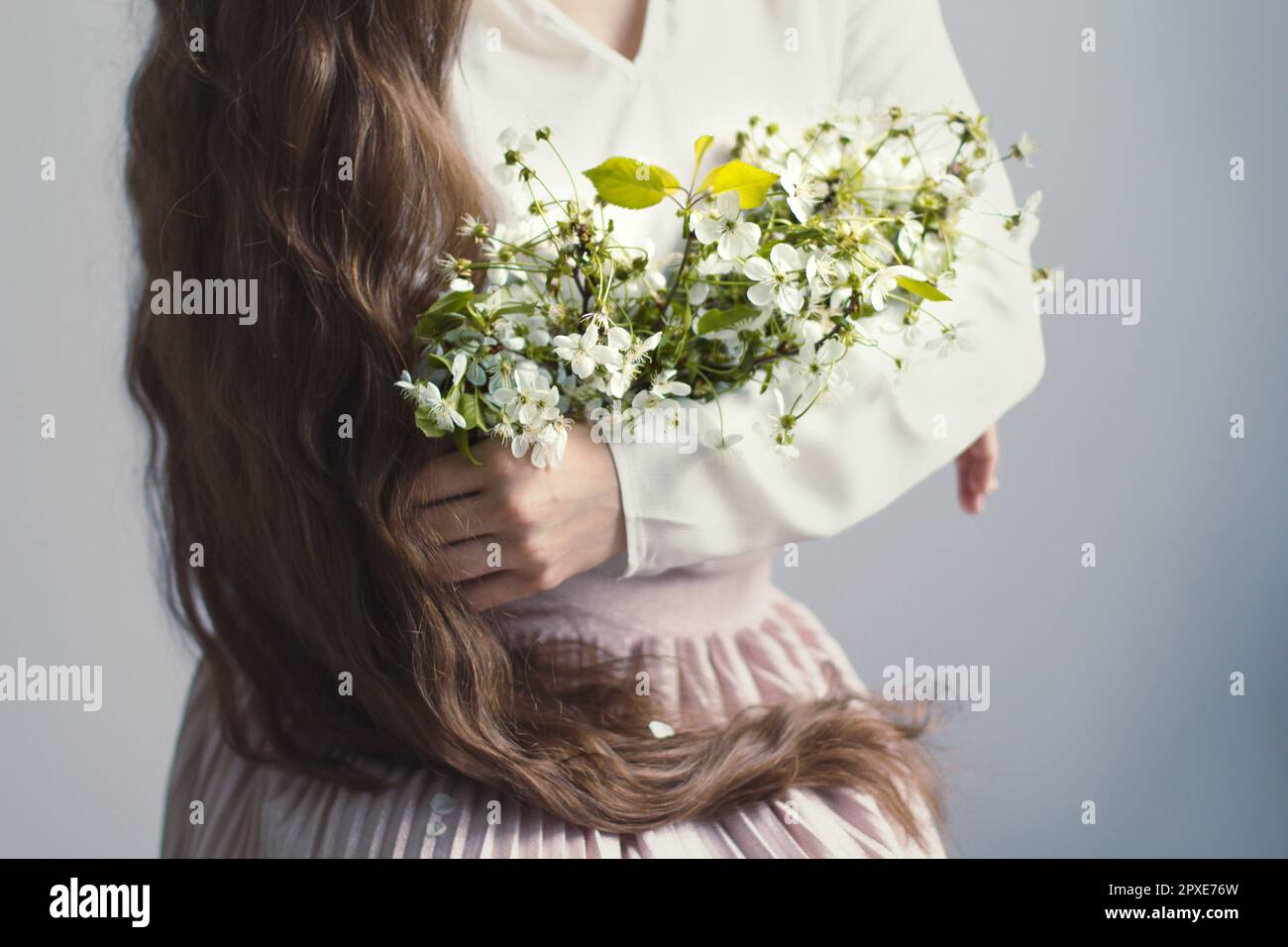 Close up woman with long hair embracing wildflowers concept photo. Romantic mood. Front view photography with blurred background. High quality picture Stock Photo