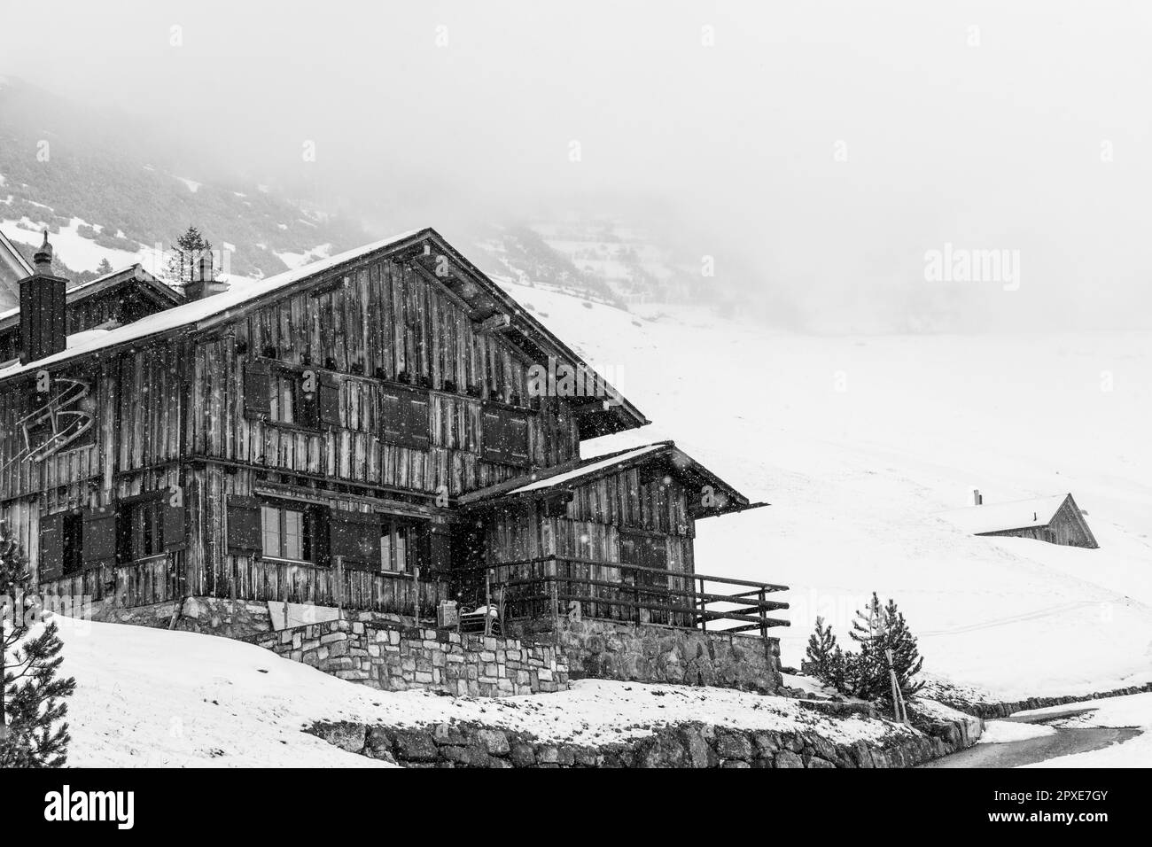 Log cabin with falling snow in the mountains Stock Photo