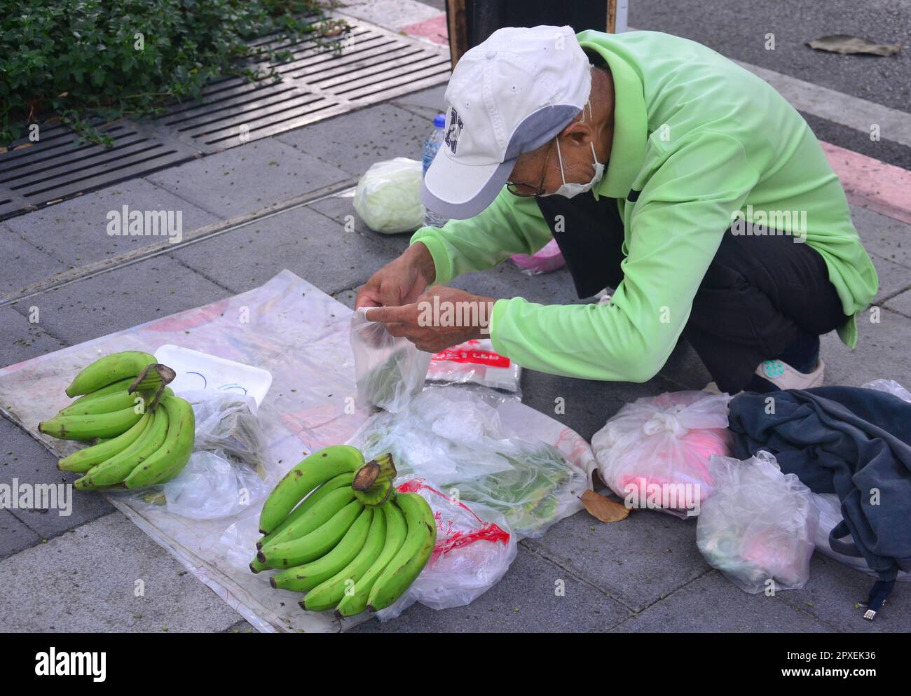 An older man sells bananas on the pavement on Silom Road, Bangkok ...