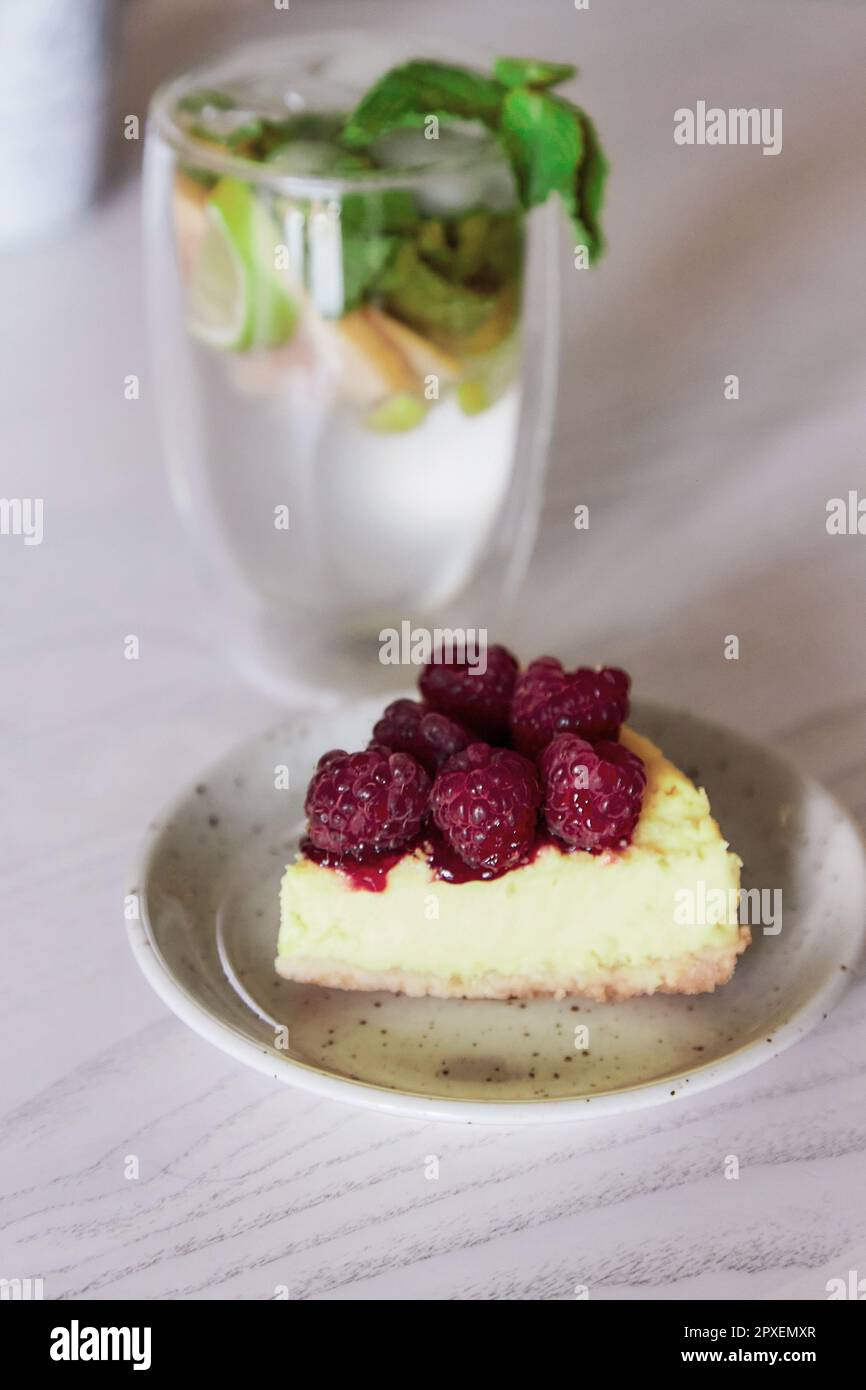 Slice of raspberry cake and non-alcoholic mojito in the cafe. Summer food. Stock Photo