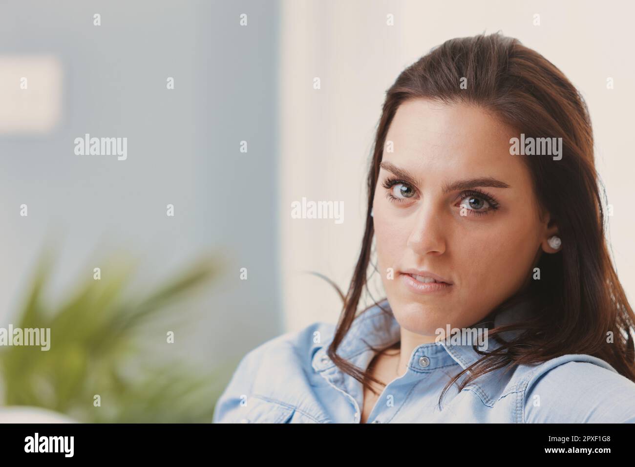 A close-up portrait of a young woman with brown hair and light-colored ...