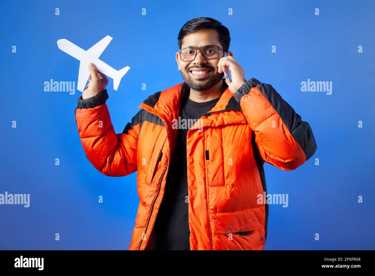 Passenger, journey, vacation. One young man clutching paper cut airplane and making phone call. Stock Photo