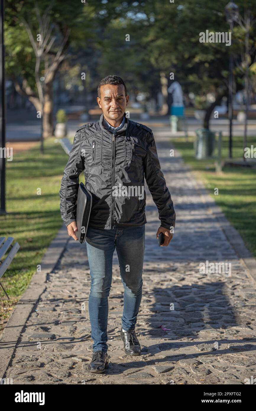 Latin young man walking through a park. Stock Photo