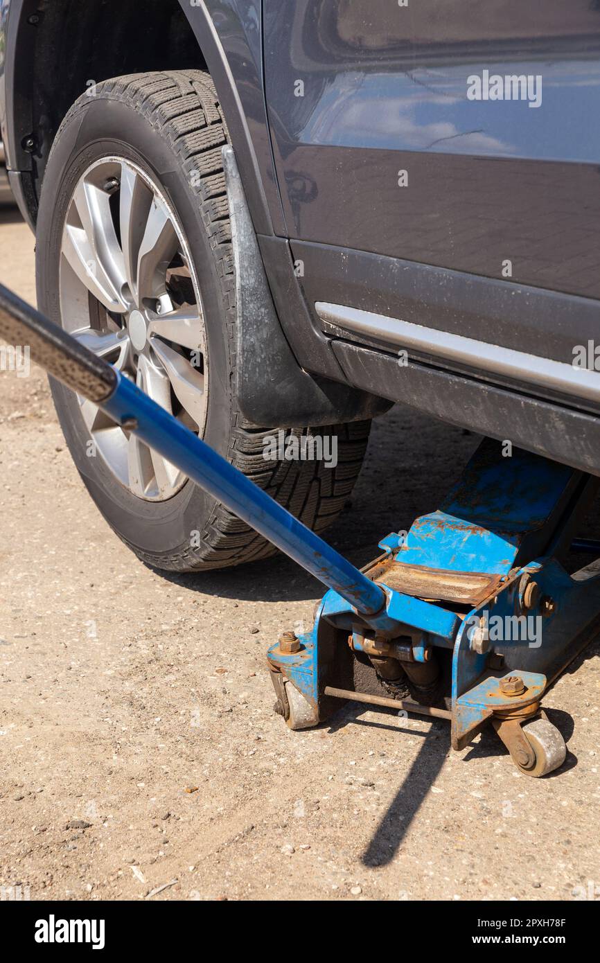 The car is raised on a pneumatic jack to change winter tires to summer tires. Tire service