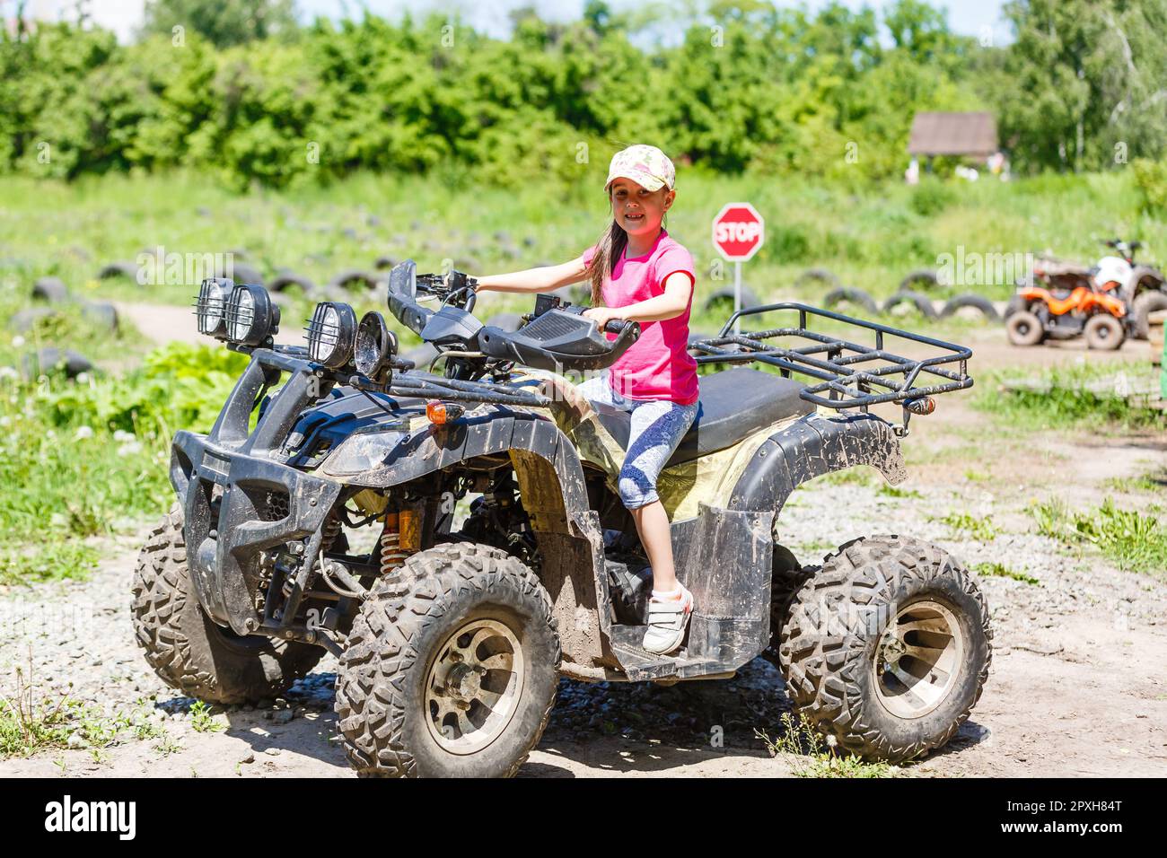 Little girl riding ATV quad bike in race track Stock Photo