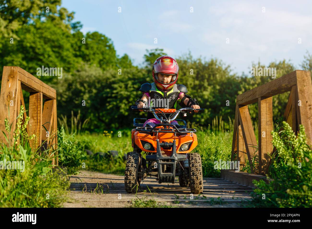 The little girl rides a quad bike. A mini quad bike is a cool girl in a