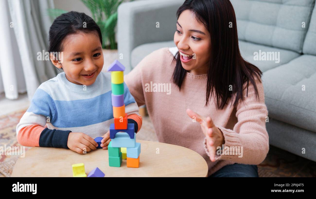 Happy Asian mother and son kid having fun playing together at home living room - Family and love concept - Soft focus on mom face Stock Photo