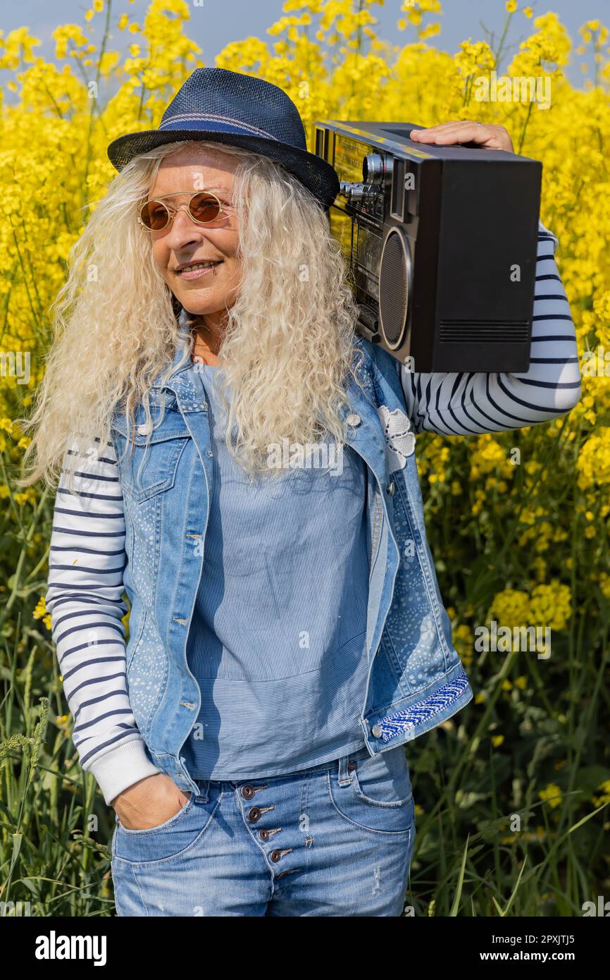 Elderly Woman have fun with vintage Boom Box in Nature. Stock Photo
