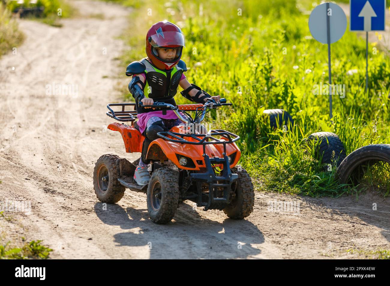 Little girl riding ATV quad bike in race track Stock Photo