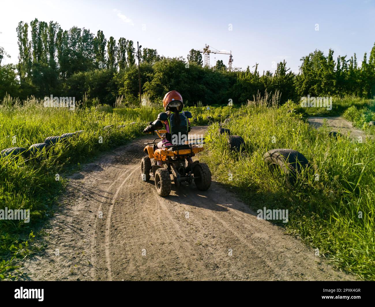 The little girl rides a quad bike. A mini quad bike is a cool girl in a