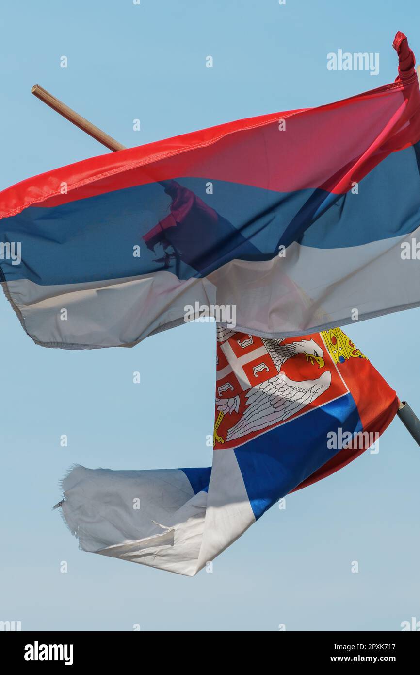 Torn and weathered flag of Serbia on a post waving in wind, selective focus Stock Photo
