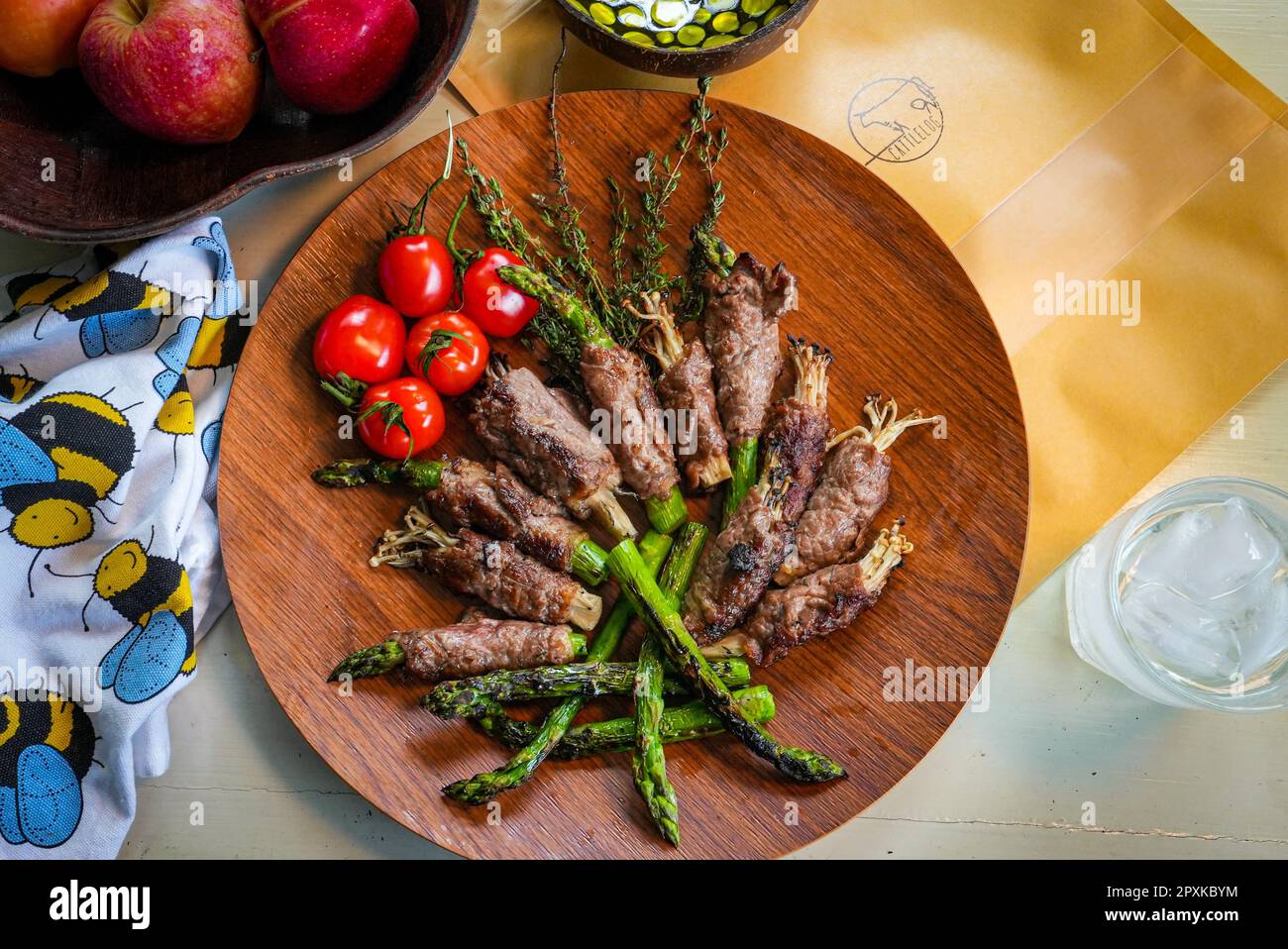 A rustic wooden plate filled with various fresh cooked meats and vegetables. Stock Photo