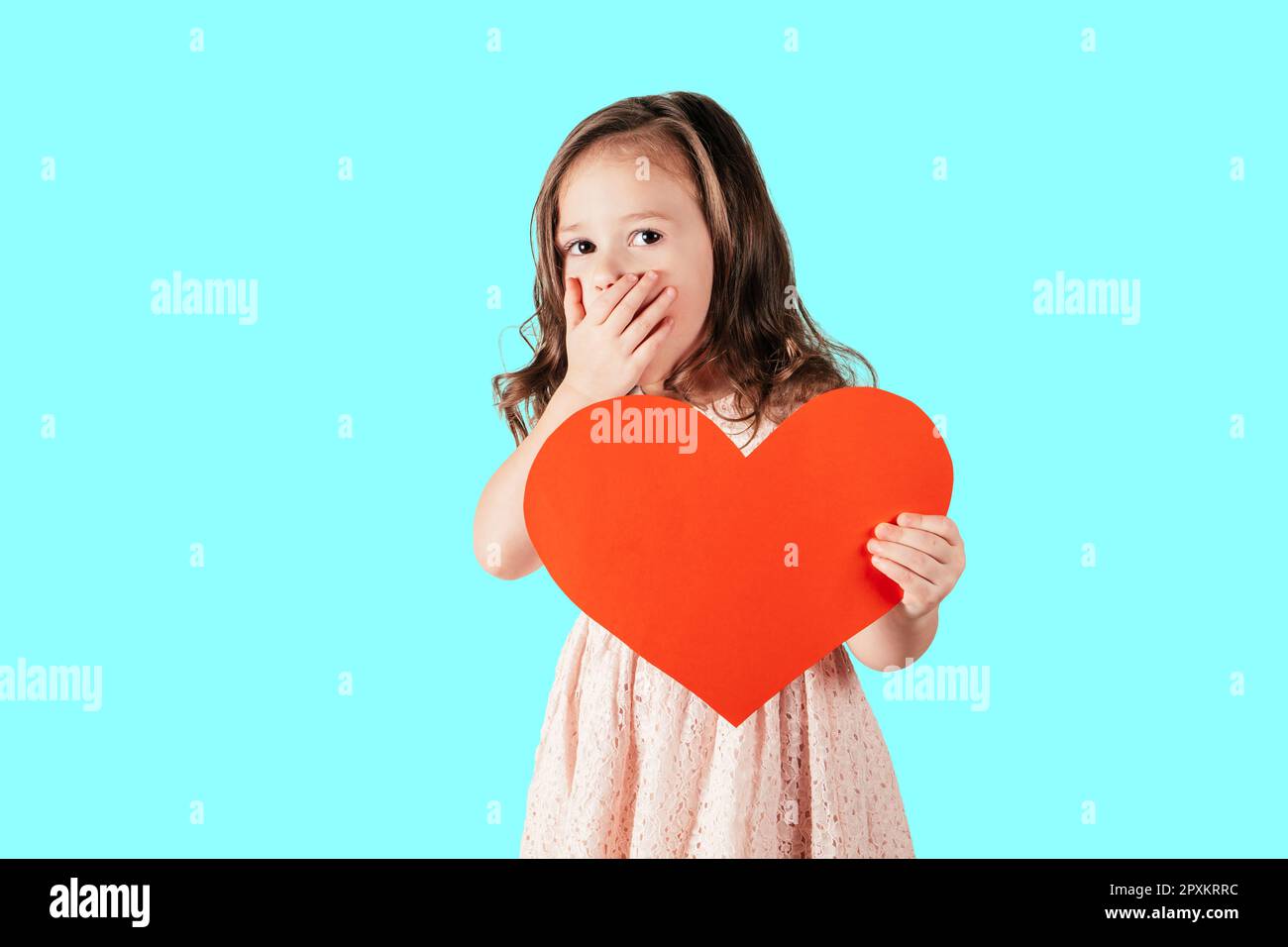 Portrait of little girl with long curly hair hold in hand red paper