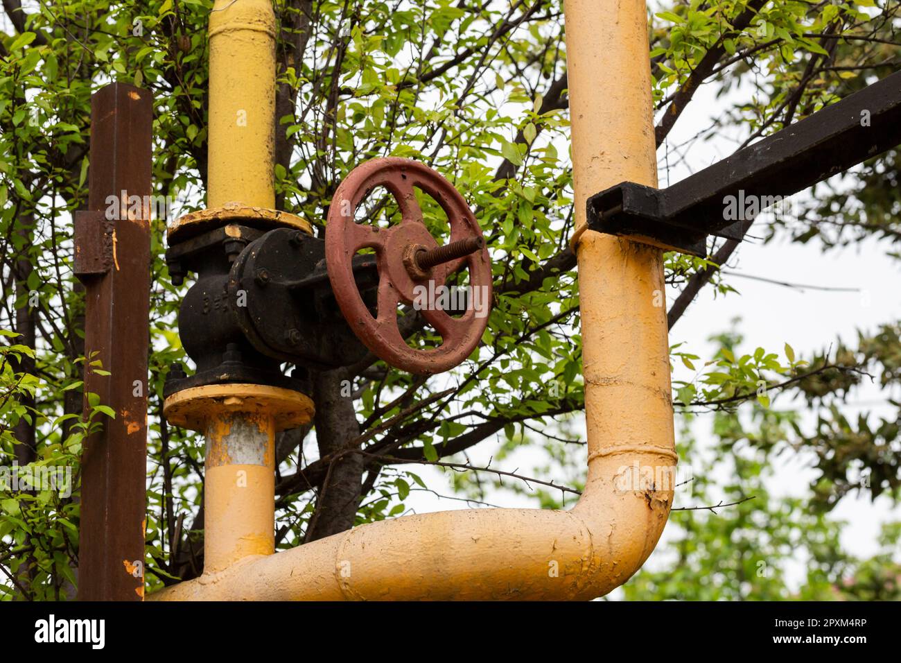 a yellow gas pipe with an old rusty valve. Gasification of housing Stock Photo