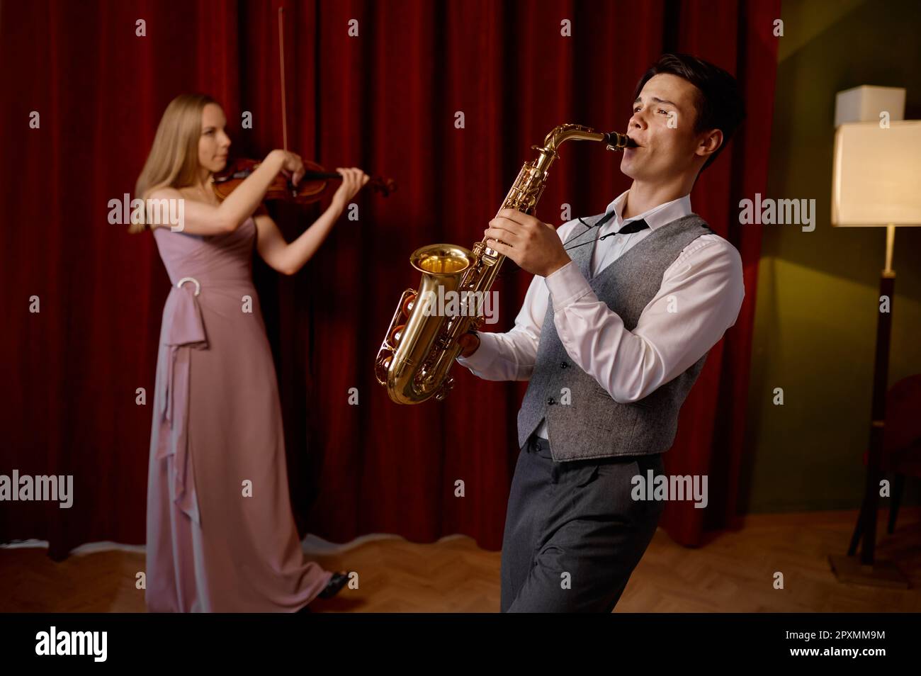 Sax man and woman fiddler duet playing classical melody. Musical duo jazz band on the stage in action Stock Photo