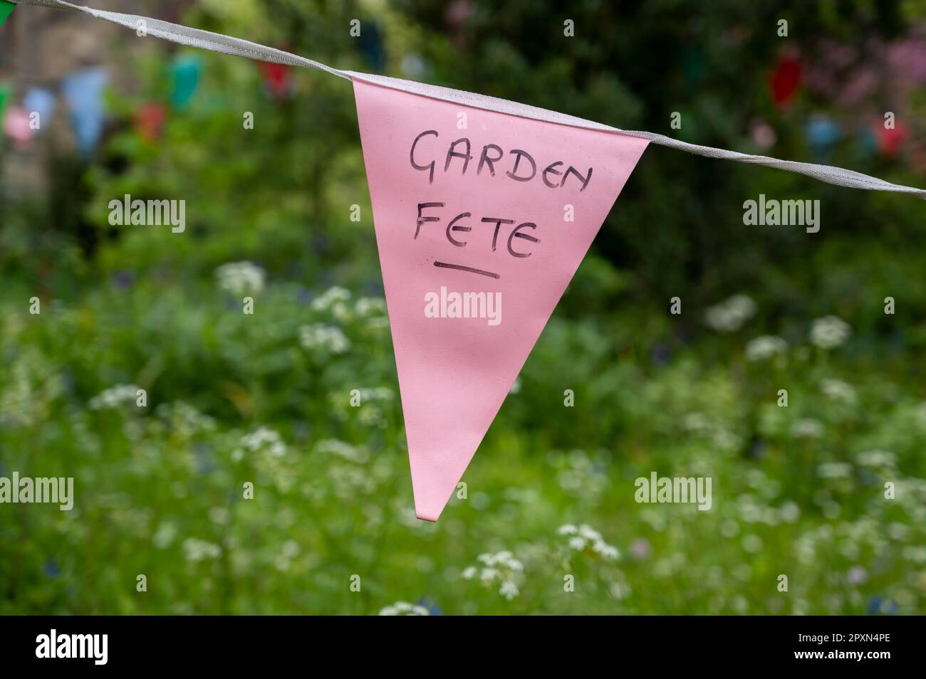 A bunting for a garden fete hanging in a garden in summer in England ...