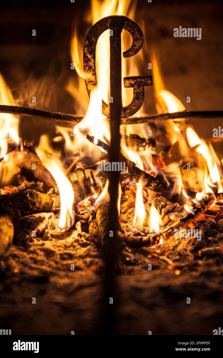 Heating branding iron for cattle over embers. Selective focus Stock