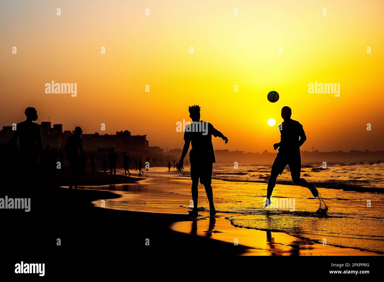 Guys play football on the beach of Dakar (Senegal) during sunset Stock Photo
