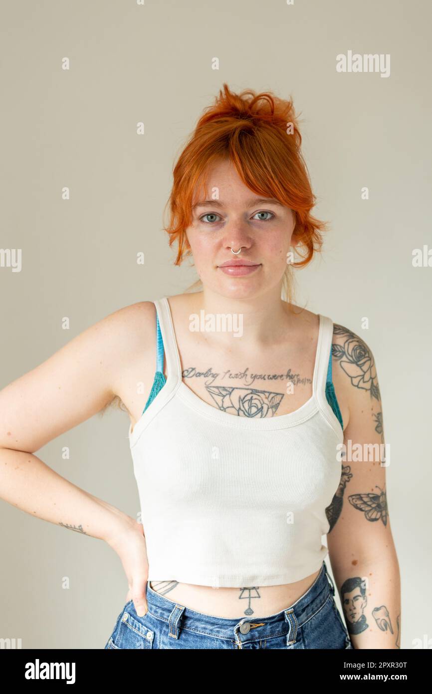A woman in her mid twenty's with dyed ginger hair, tattoos and and nose ring Stock Photo