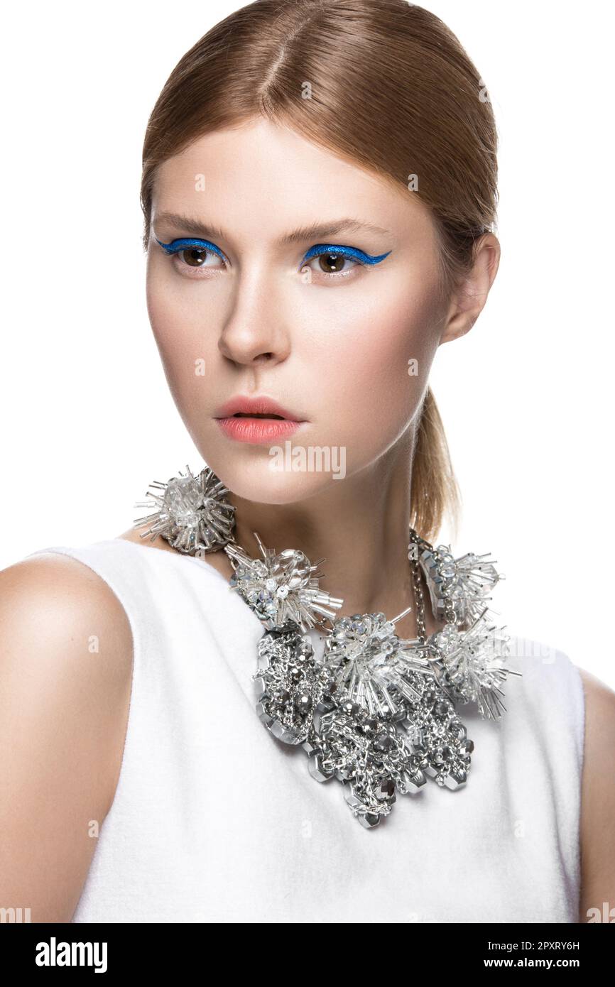 Beautiful fashionable girl with the blue arrows on the eyes, smooth hair and original decoration around her neck. Model in white. Beauty face. Picture Stock Photo