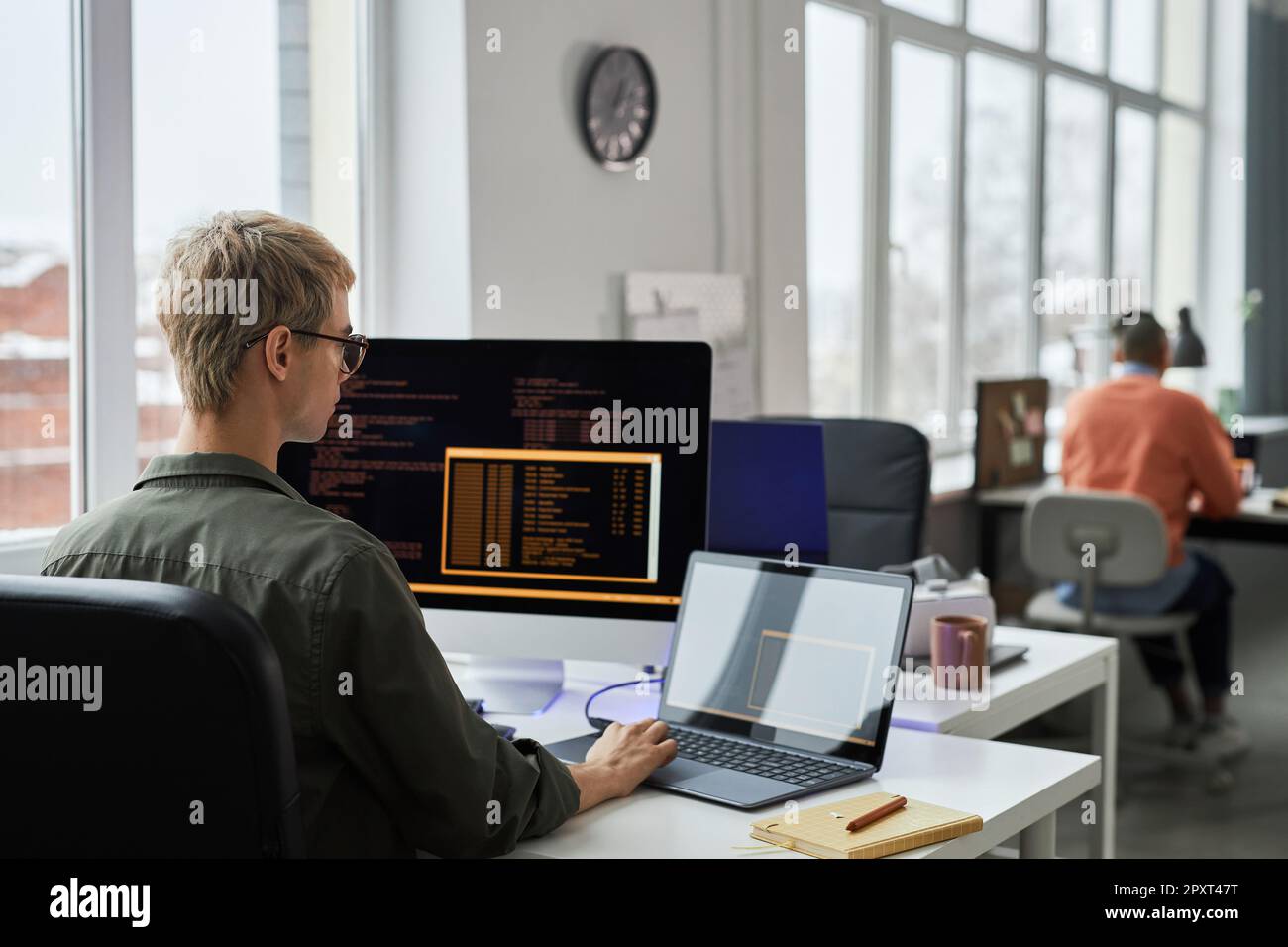 Young programmers writing codes on computer sitting at their workplace during working day in IT office Stock Photo