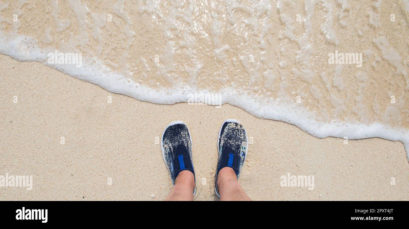 Female feet wearing water shoes or swimming shoes on the beach. Stock Photo