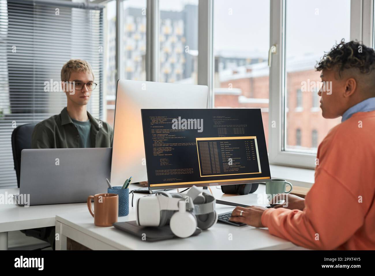 Young colleagues working with security computer codes sitting at table in IT office Stock Photo