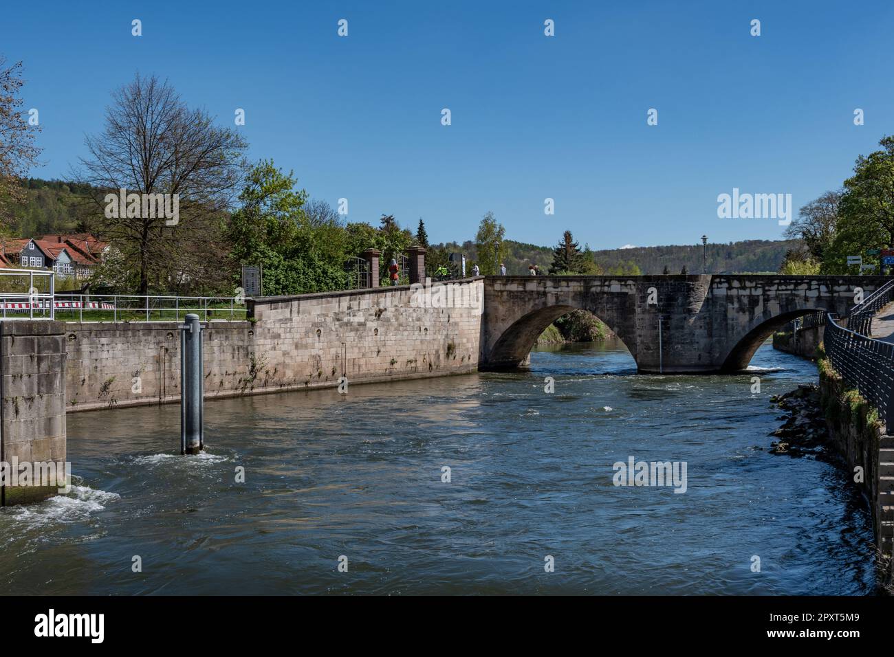 The Werra flows calmly between the high walls that surround the river and under the beautiful old Werra bridge. The cloudless sky shines in a deep blu Stock Photo