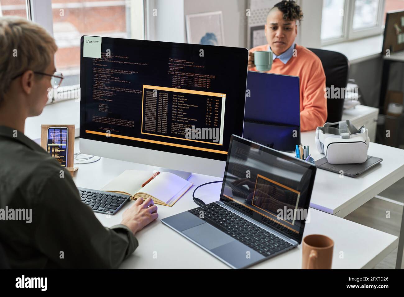 Young programmers writing codes for computer program on computers sitting at workplace in office Stock Photo