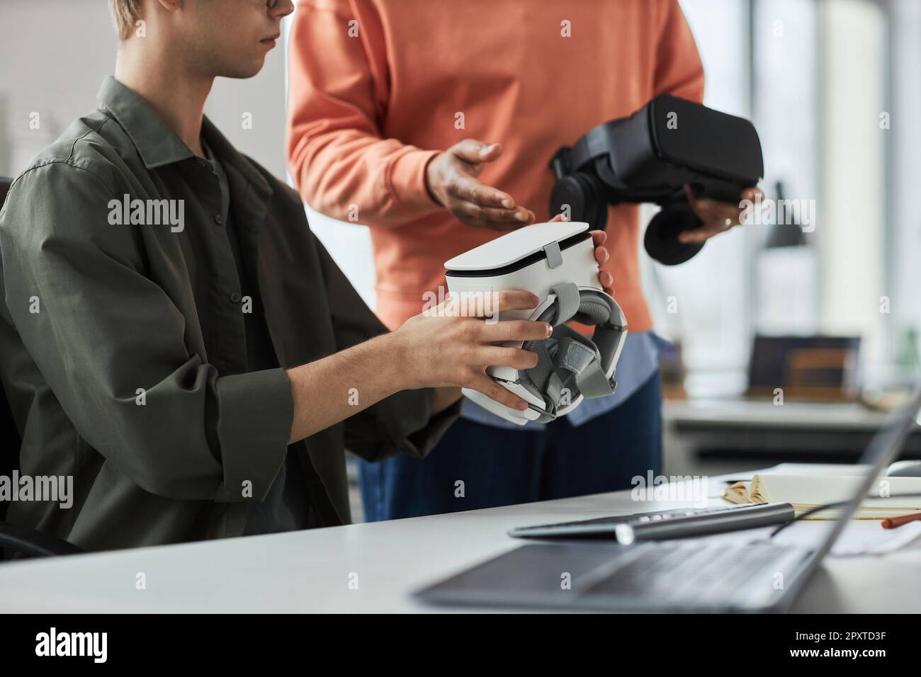 Close-up of two programmers testing new computer program in VR glasses during teamwork in office Stock Photo