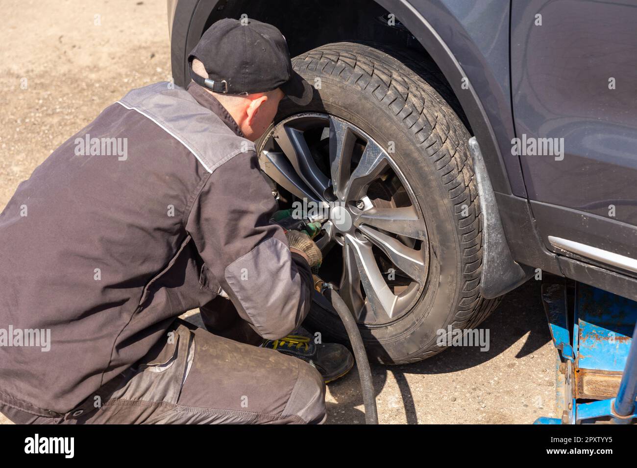 Mechanician changing car wheel in auto repair shop. Close up of