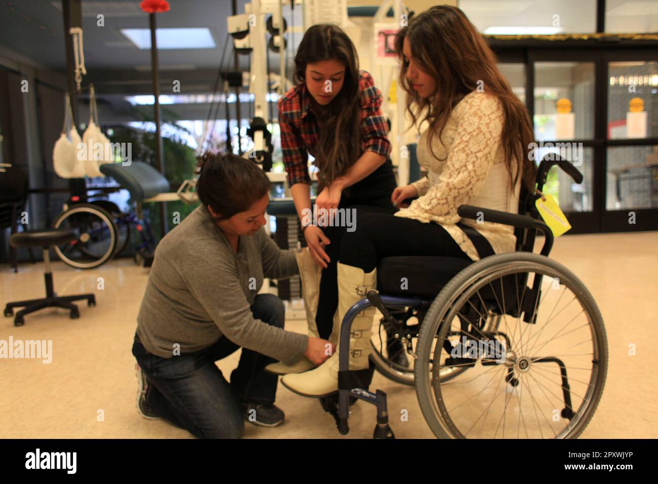 Katy Sharify (left), who received stem cell therapy before the study she  was part of was cancelled, moves between exercise machines in the Cypress  Semiconductor Spinal Cord Rehabilitation Gym with help from