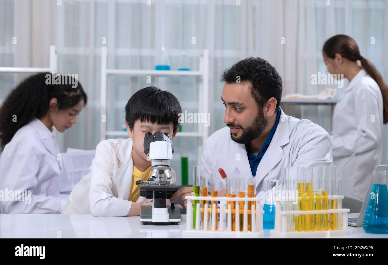 Kid boy wearing white laboratory coat and learning how to use