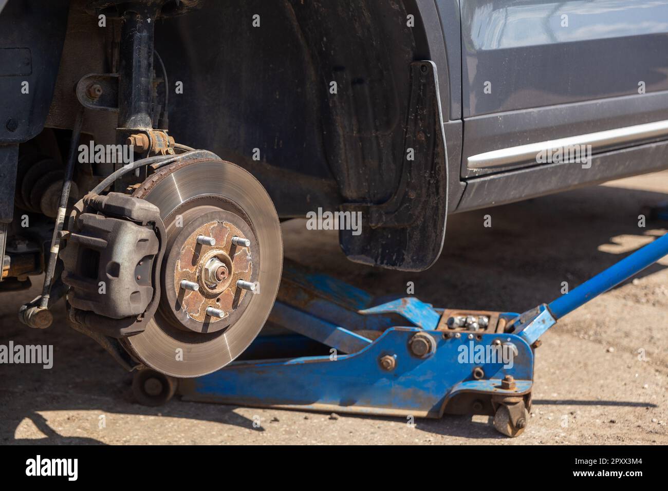 Car on tire mounting with removed wheel on pneumatic jack, seasonal