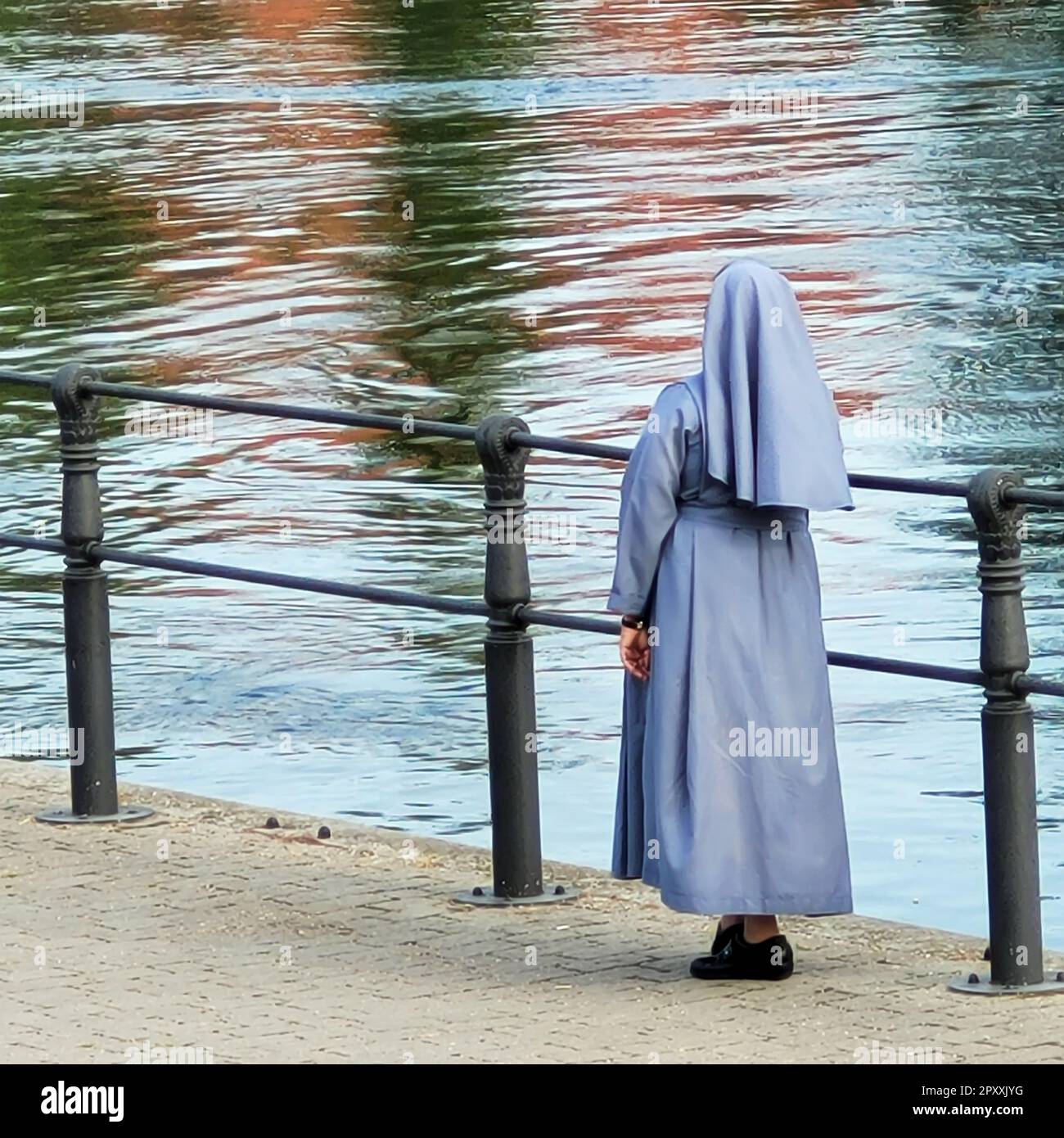 A nun stands by a river and looks at the water Stock Photo - Alamy