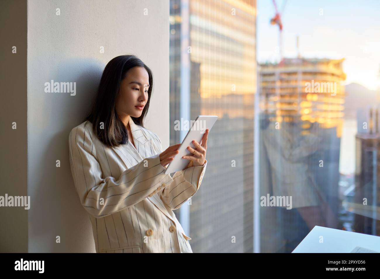 Young Asian business woman manager using tablet standing in corporate office. Stock Photo