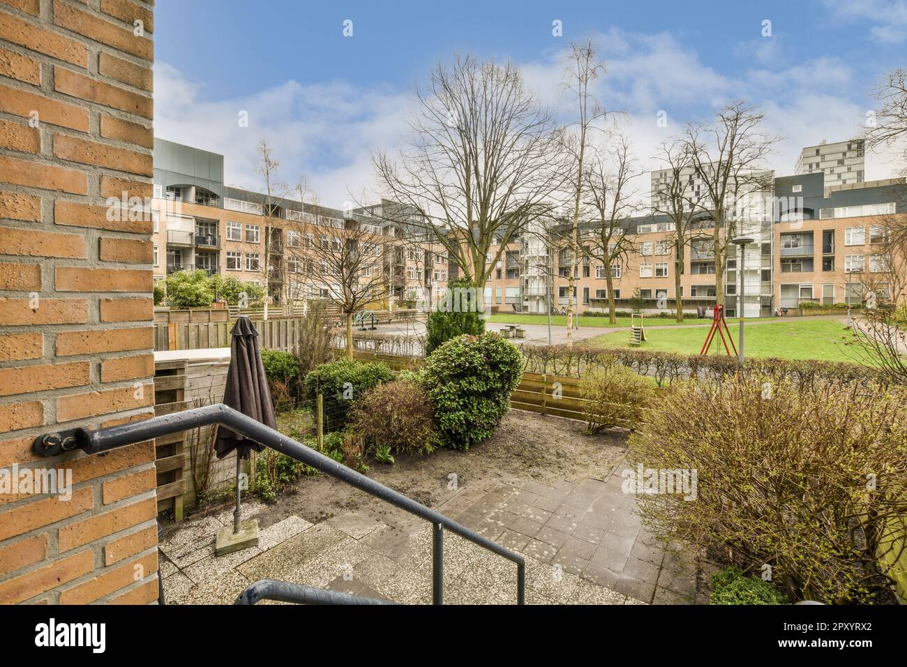 an outside area with trees and bushes in the foreground, taken from a window looking out onto some buildings Stock Photo