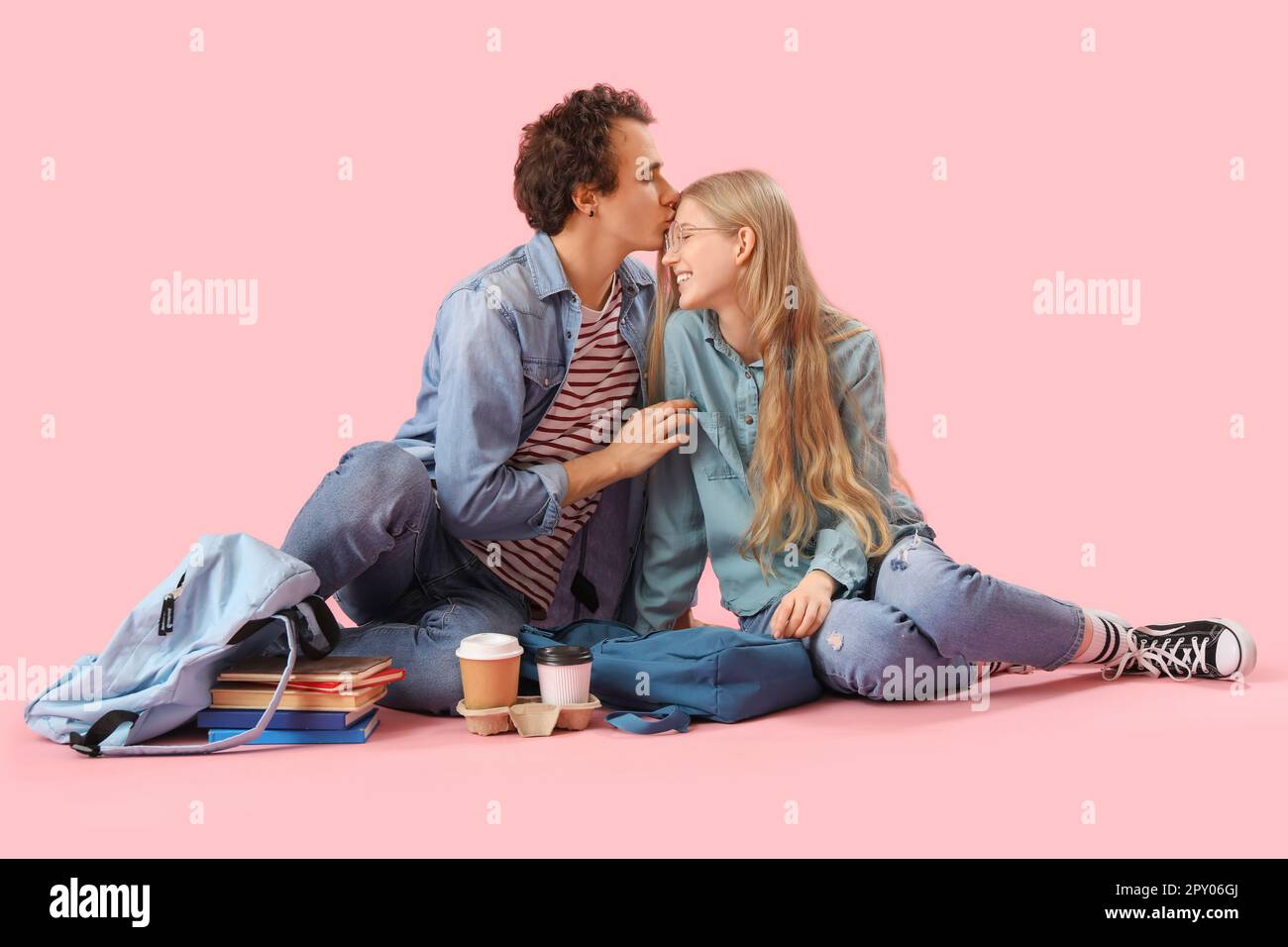 Teenage couple sitting on pink background Stock Photo