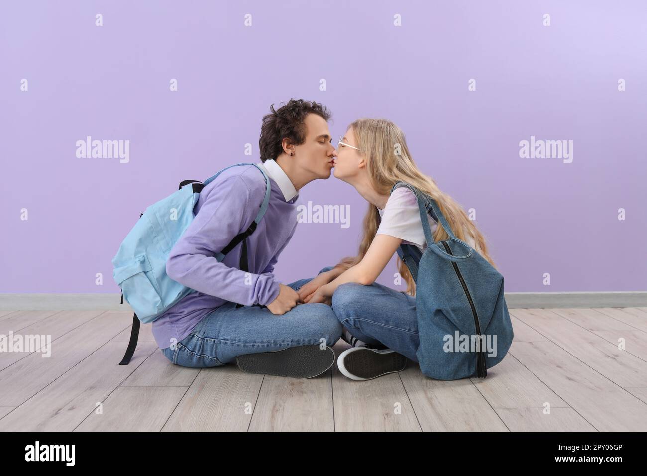 Teenage couple kissing near lilac wall Stock Photo